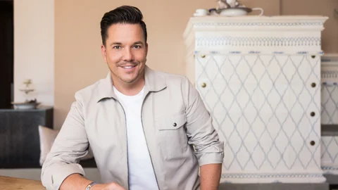 Sven Epiney sitzt an einem Tisch in einem hellen Hemd.