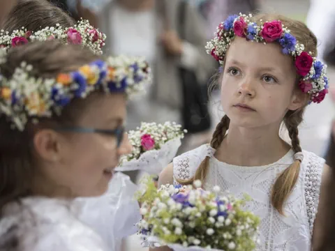 Mädchen mit Blumenkränzen im Haar bei einer Feier.