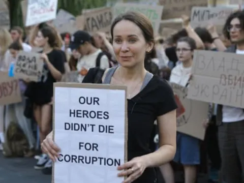 Frau hält Protestplakat in einer Menschenmenge.