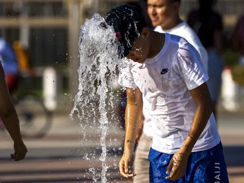 Junge mit Baseballkappe unter Brunnenstrahl.