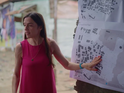 Frau zeigt auf Stadtplan an Wand im Freien.