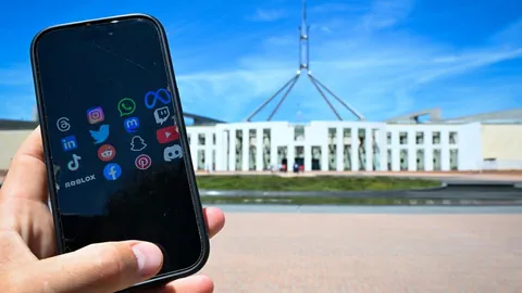 Symbolbild: Ein Smartphone in einer Hand, im Hintergrund das australische Parlament in Canberra.