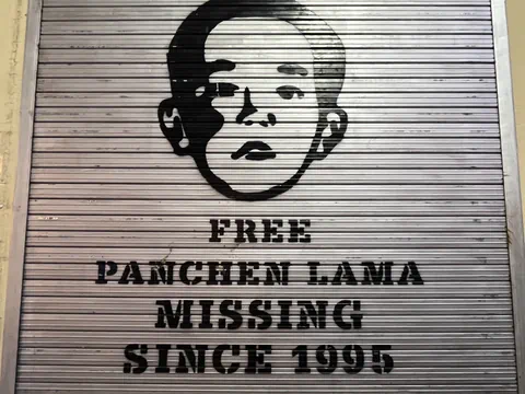 Graffiti eines Gesichts mit Schriftzug 'Free Panchen Lama Missing Since 1995'.
