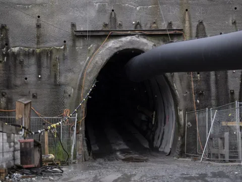 Tunnelöffnung mit grossem Rohr davor.