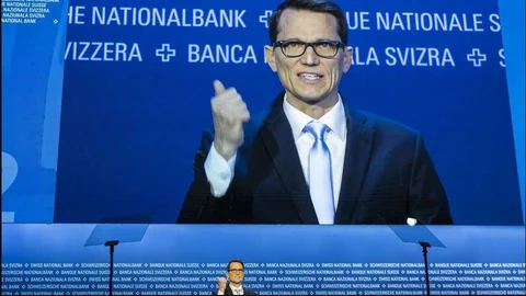 Mann steht vor einer Leinwand mit Schrift der Schweizerischen Nationalbank.