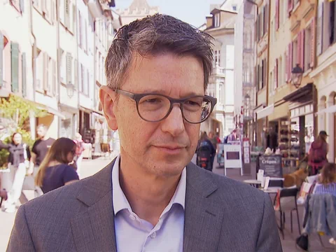 Mann mit Brille in einer belebten Strasse.