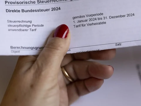 Hand hält Steuerrechnung für die direkte Bundessteuer 2024.