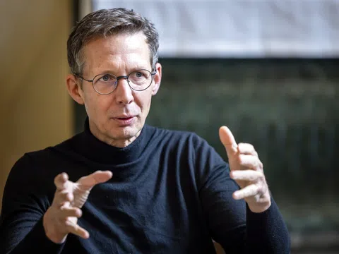 Person mit Brille und schwarzem Pullover gestikuliert.