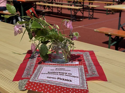 Blumen im Glas, Notizen und Tischdecken auf Holztisch im Freien.