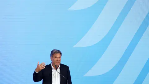 Mann hält Rede vor blauem Hintergrund.