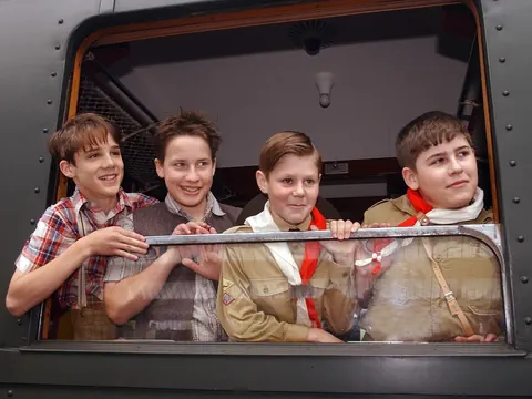 Vier Jungen schauen aus einem Zugfenster.