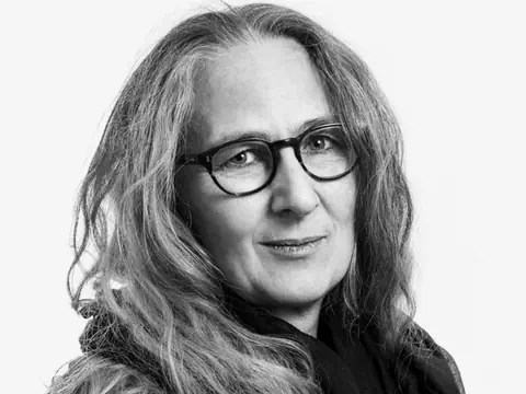 Lächlende Dame mit Brille und langem grauen Haar