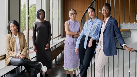 Fünf Frauen in formeller Kleidung in einem Büro.