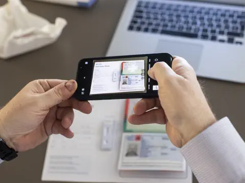 Mann mit iphone und Pass und Laptop