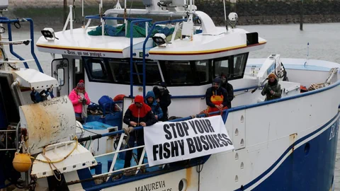 Fischer protestieren auf einem Schiff mit einem Banner «Stop your fishy business»