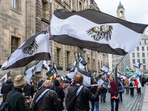 Menschenmenge mit schwarz-weissen Fahnen bei einer Demonstration auf der Strasse.
