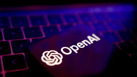 Smartphone mit OpenAI-Logo auf Laptop-Tastatur beleuchtet.