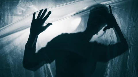 Symbolbild: eine Person im Gegenlicht kämpft mit Plastikfolie.