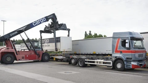 Container wird von einem Lkw auf einen Zugwagen geladen.