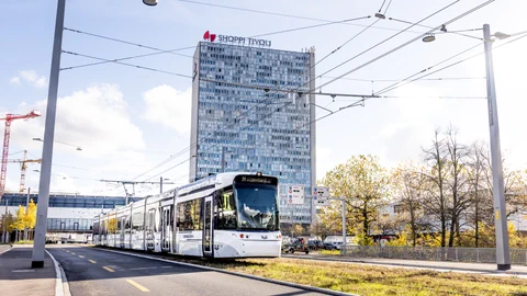 Weisses Tram vor einem Hochhaus mit 'SHOPPI TIVOLI'-Schriftzug.