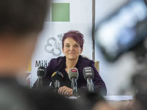 Frau bei einer Pressekonferenz mit Mikrofonen.