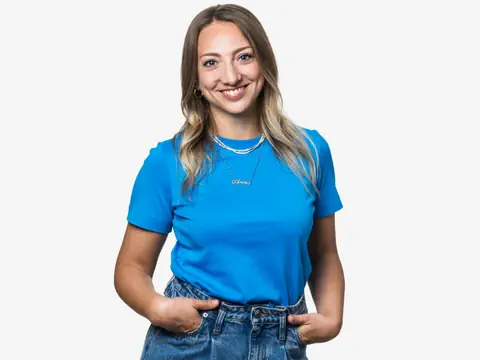 Moderatorin Anna Zöllig lacht in die Kamera, die Hände in den Hosentaschen