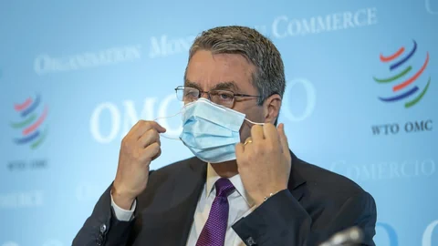 Mann mit Anzug und Krawatte zieht sich eine Schutzmaske über Mund und Nase