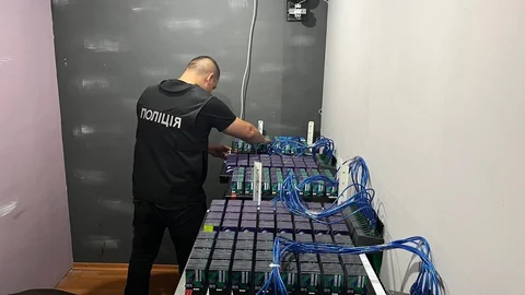 Polizist schaut sich Kisten voller mit Kabel verbundener Geräte an.