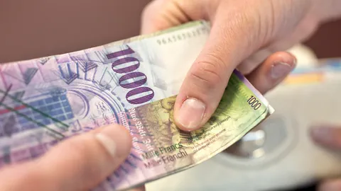 Zwei Hände übergeben sich eine Banknote im Wert von Tausend Franken.