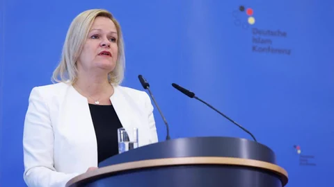 Nancy Faeser an einem Rednerpult vor blauem Hintergrund.