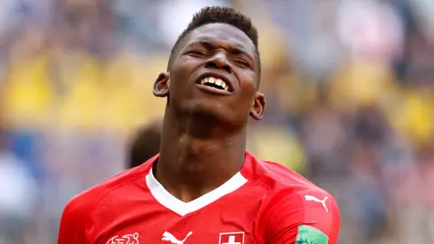 Fussballspieler im roten Trikot zeigt emotionale Reaktion auf dem Spielfeld.