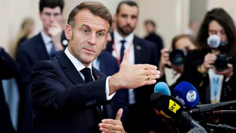 Macron spricht in Mikrofone und gestikuliert.