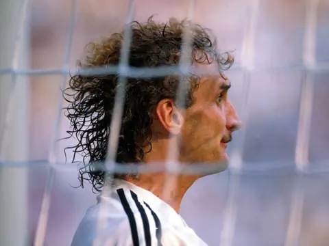 Fussballspieler mit lockigem Haar im Torraum.