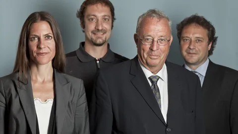 Portraitbild von einer Frau und drei Männern vor grauem Hintergrund. 