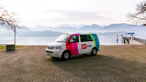 Der SRF Kids Bus vor einem See.