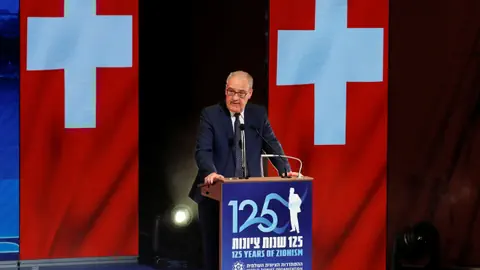 Parmelin an Rednerpult vor Schweizerfahnen.