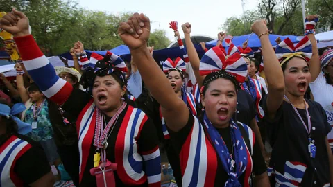 Anti-Regierungs-Demonstranten in thailändischen Farben recken Fäuste in den Himmel