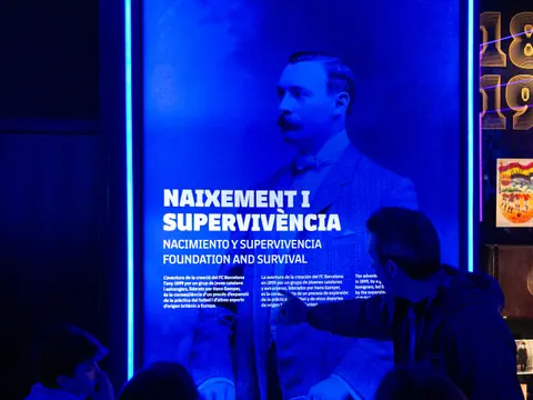 Person zeigt auf blau beleuchtetes historisches Poster mit Text.