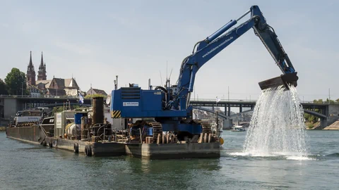 Kran auf dem Rhein, der etwqas aus dem Wasser holt.