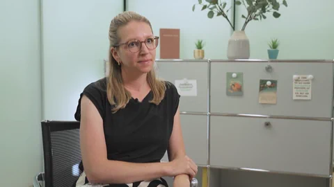 Person sitzt in modernem Büro mit Pflanzen im Hintergrund.