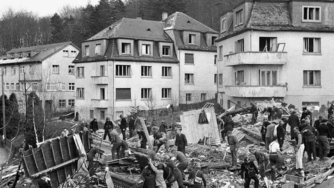 Menschen durchsuchen die Trümmer von Häusern