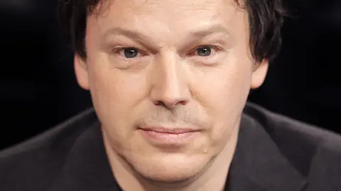 Ein Mann mit ebenmässigem Gesicht, den Mund geschlossen, die Augen stehen nahe beienander.