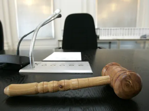 Richtertisch mit Hammer und Mikrofon in einem Sitzungssaal.