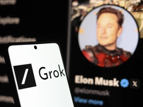 Smartphone mit Grok-Logo, verschwommener Bildschirm im Hintergrund.