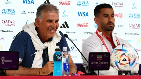 Der Nationaltrainer Irans, Carlos Queroz, und sein Verteidiger, Ehsan Hjsafi, sprechen an Pressekonferenz.