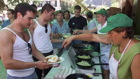 Köchinnen schöpfen jungen Männern Rösti und Spiegeleier.