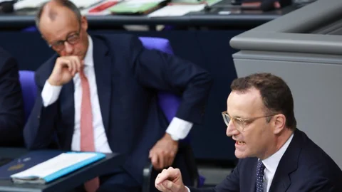 Zwei Männer in Anzügen während einer Diskussion in einem Konferenzraum.