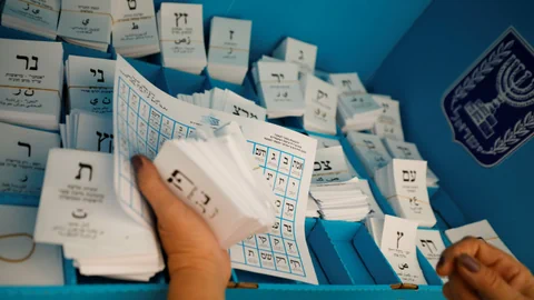 Eine Person sortiert aufgestapelte Wahlzettel.