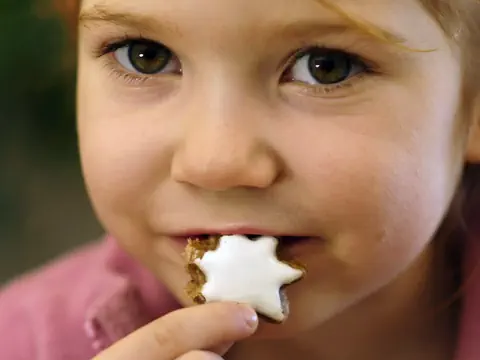 Ein Kind isst einen Zimtstern.