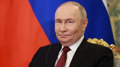 Mann in Anzug vor russischer Flagge.